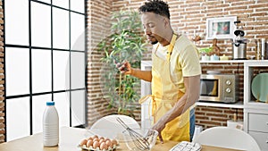 African american man chef looking online recipe on smartphone at dinning room