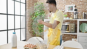 African american man chef looking online recipe on smartphone at dinning room