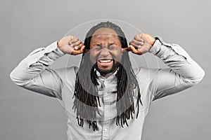 African-American man closing ears isolated on grey