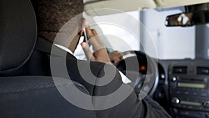 African-American man communicating by smartphone while driving car, back view