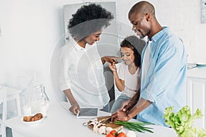 african american man cutting fresh vegetables for breakfast with family standing near by in kitchen