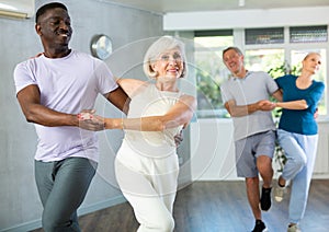 African-American man dances steamy salsa with elderly female companion for fitness classes photo