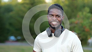 African American man demonstrates toothy smile in green park