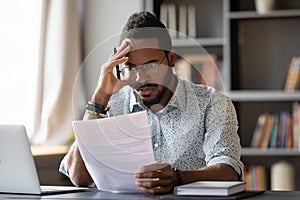 African American man dissatisfied by bad news received in letter