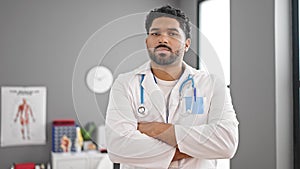 African american man doctor standing with serious expression and arms crossed gesture at clinic