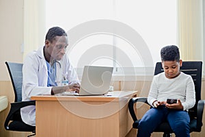 African American man doctor using laptop and paperwork checking report at table office hospital. Doctor making data analysis