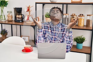 African american man doing yoga exercise sitting on table at home