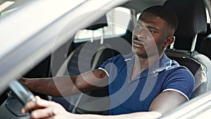 African american man driving car with serious face at street