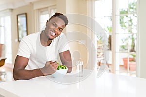 African american man eating fresh healthy salad with a happy face standing and smiling with a confident smile showing teeth