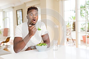 African american man eating fresh healthy salad scared in shock with a surprise face, afraid and excited with fear expression