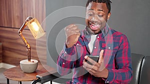 african american man is enjoying by good news and win in mobile game, portrait with smartphone