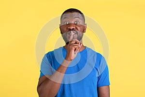 African American Man Gesturing Hush Sign Posing Over Yellow Background