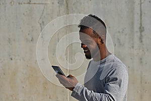 African american man in a gray t-shirt consulting social networks on his cell phone