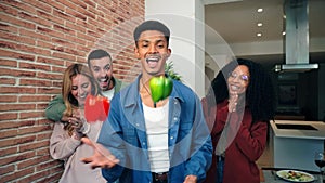 African american man havinf fun with his friends juggling with peppers at home. Slow motion of a funny guy playing with
