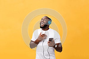 African American man with headphones listen and dance with music. Isolated on yellow background