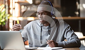 African American man in headphones making video call in cafe