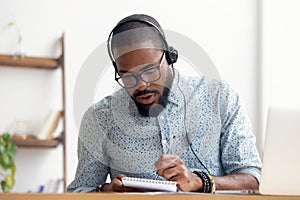 African American man in headphones taking E-learning course at office