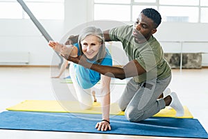 African American man helps mature lady athlete with posture