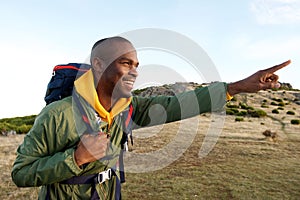 African american man hiking with backpack and pointing in direction