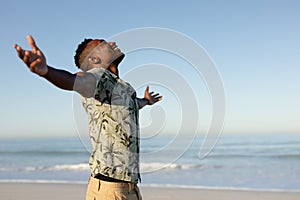 An African American man with his arms outstretched on beach on a sunny day photo