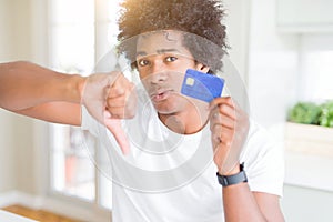 African American man holding credit card with angry face, negative sign showing dislike with thumbs down, rejection concept