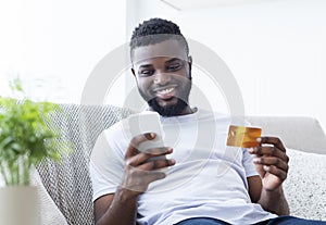 African american man holding credit card and cellphone