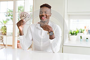 African american man holding fifty dollars bank notes very happy pointing with hand and finger