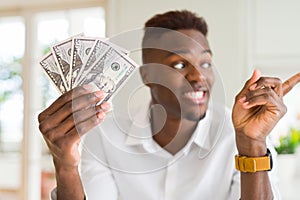 African american man holding fifty dollars bank notes very happy pointing with hand and finger to the side