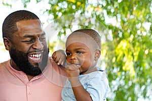 African American man holding his son and smiling.