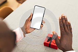 African American man holding a smartphone with a blank screen with copy space on video call