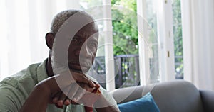 African American man holding walking stick while sitting on the couch at home