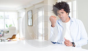 African American man at home angry and mad raising fist frustrated and furious while shouting with anger