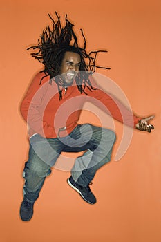 African-American man jumping and playing air guitar.