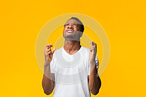 African American Man Keeping Fingers Crossed Standing Over Yellow Background