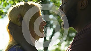 African-american man kissing and hugging his blonde woman with tenderness