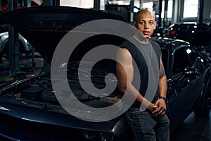 African American man leaning on car with opened hood