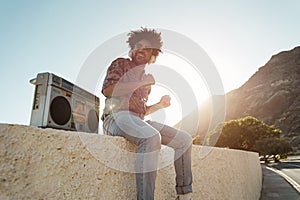 African american man listening music with vintage boombox stereo outdoor on the beach - Focus on face