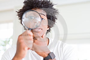 African American man looking through magnifying glass serious face thinking about question, very confused idea