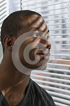 African American man looking out window and smiling, vertical