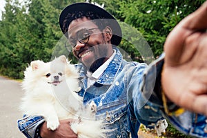 African american man making self portrait with fluffy spitz in summer spring park
