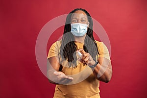 African American man in mask spraying sanitizer