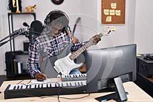 African american man musician composing song playing electrical guitar at music studio