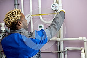 African American man in overalls carefully takes measurements with tape measure