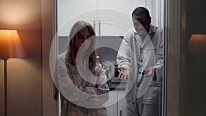 African-American man in pajamas yell at sad young wife standing in kitchen