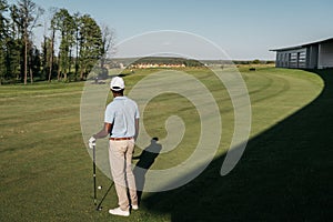 African american man playing golf with club and ball at green lawn