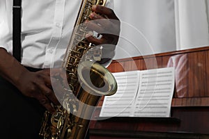 African-American man playing saxophone indoors, closeup with space for text. Talented musician