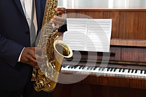 African-American man playing saxophone indoors, closeup with space for text. Talented musician