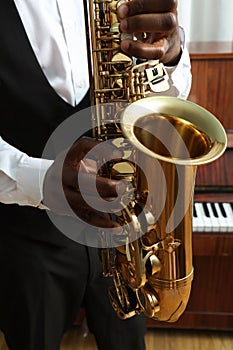 African-American man playing saxophone indoors, closeup. Talented musician