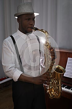 African-American man playing saxophone indoors. Talented musician