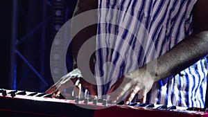 African American man plays piano synthesizer and sings in dark studio with blue lights. Musician with white ethnic